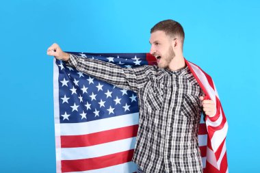 Genç adam bir Amerikan bayrağı mavi arka plan üzerinde tutan