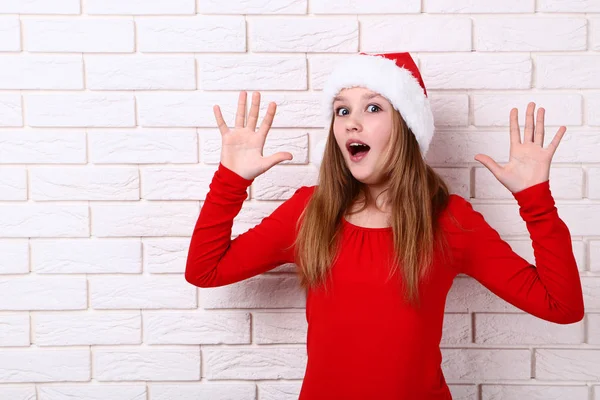 Verrast Meisje Kerstmuts Bakstenen Muur Achtergrond — Stockfoto