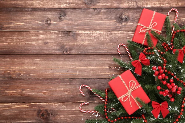 圣诞冷杉树枝与糖果棒和礼品盒在棕色木桌上 — 图库照片