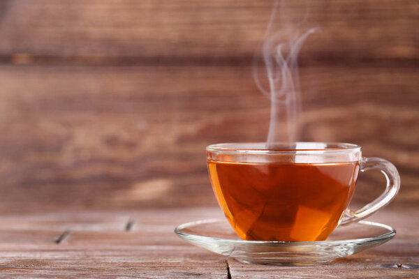 Cup of tea with steam on brown wooden table