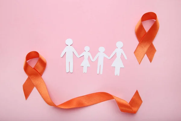 Orange ribbons with paper family. Medicine concept