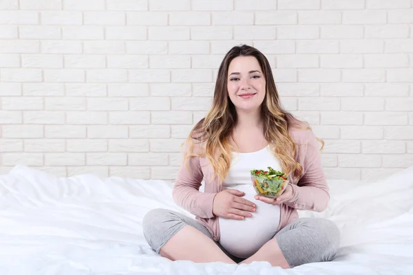 Mooie Zwangere Vrouw Met Salade Kom Zittend Bed — Stockfoto
