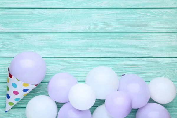 Rubber balloons with birthday paper cap on wooden table