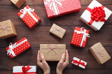 Kahverengi ahşap masa üzerinde hediye kutuları ile eller