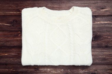 Beyaz kazak kahverengi ahşap masa üzerinde katlanmış