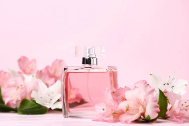 Parfüm şişesi ile pembe ahşap masaya alstroemeria çiçek