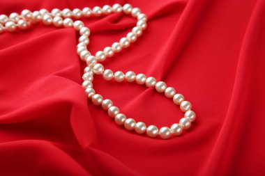 Kırmızı saten kumaş üzerine inci kolye