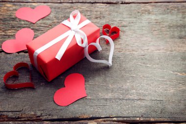Tahta masada kırmızı kalpler olan hediye kutusu.
