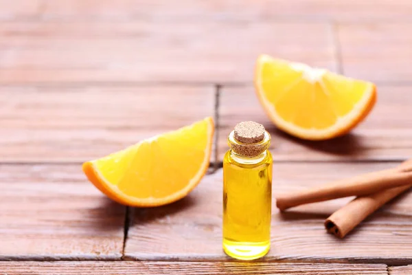 Orange oil in bottle with cinnamon sticks on brown wooden table