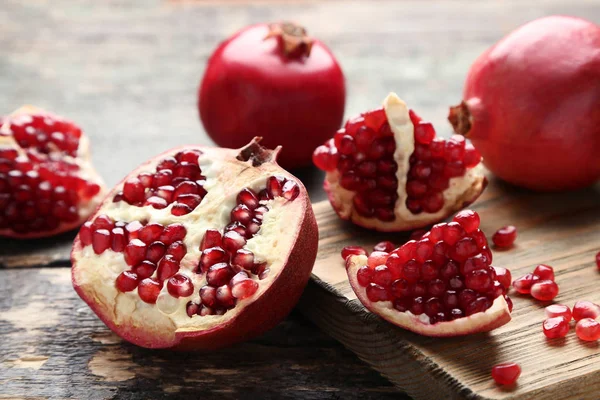 Olgun ve sulu nar ile kesme tahtası üzerinde gri ahşap masa