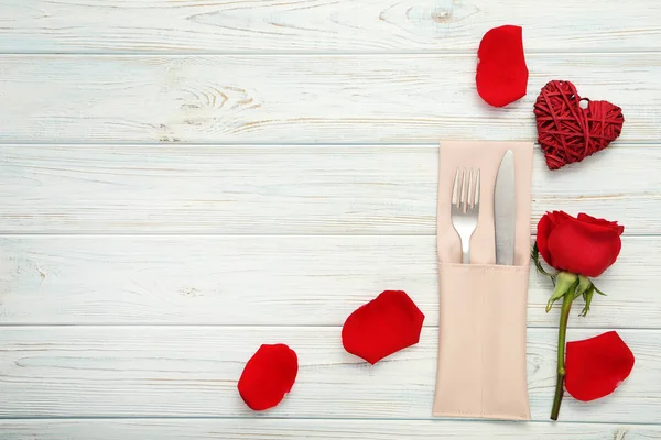 フォークとナイフの木製のテーブルの赤いバラと — ストック写真