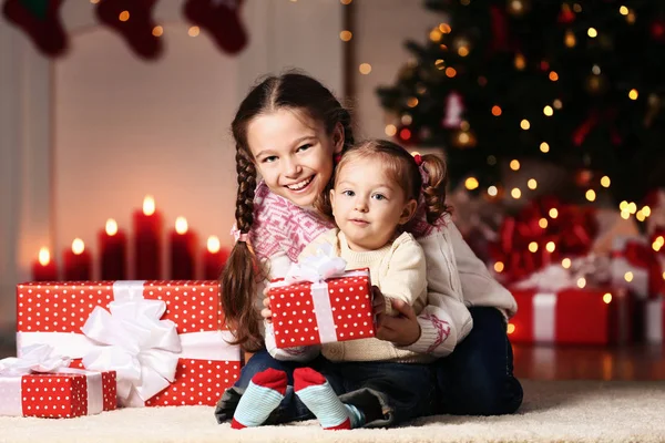 stock image Beautiful two sisters with gift boxes sitting near christmas tree at home