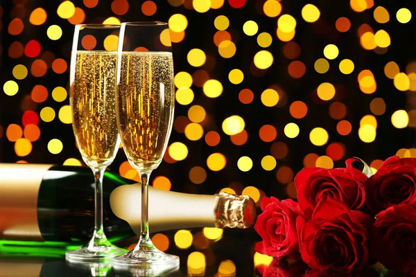 ガラスとライトの背景に赤いバラの花束とシャンパン ボトル — ストック写真