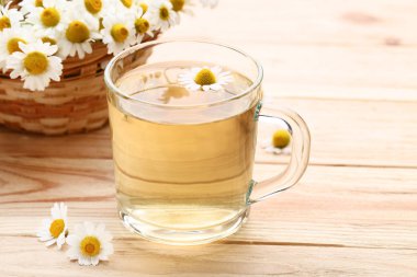 Kahverengi ahşap masa üzerinde papatya çiçeği ile çay