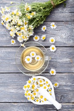 Gri ahşap masa üzerinde papatya çiçeği ile çay