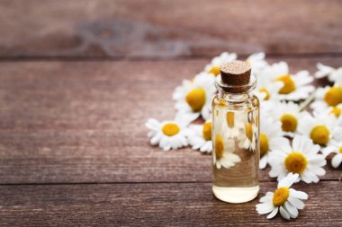 Papatya yağı ile kahverengi ahşap masaya çiçek şişe