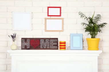Fotoğraf çerçeveleri, yeşil bitkiler ve word ev beyaz şömine