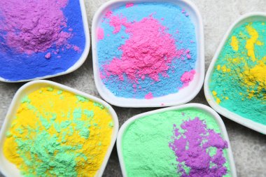 Colorful holi powder in bowls on grey background clipart