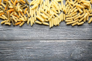 Gri ahşap masa üzerinde farklı pişmemiş makarna