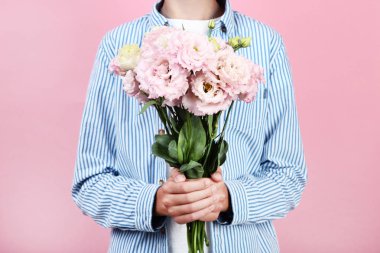 Pembe bir arka plan üzerinde eustoma çiçekli genç çocuk