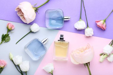 Parfüm şişeleri çiçeklerle renkli arka plan üzerinde