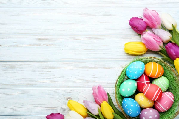 Sepeti ahşap masa üzerinde Lale ile renkli Paskalya yumurtaları