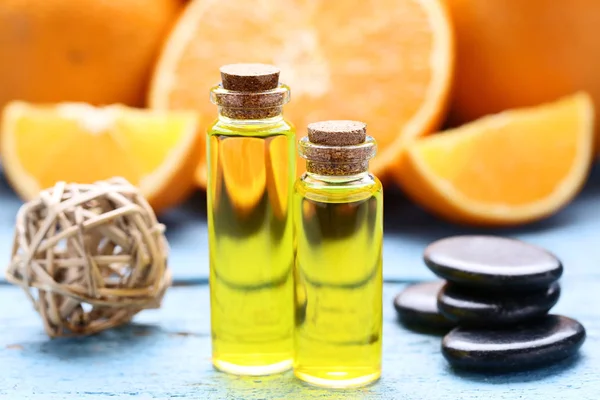 Orangenöl Flaschen Mit Wellnesssteinen Auf Blauem Holztisch — Stockfoto