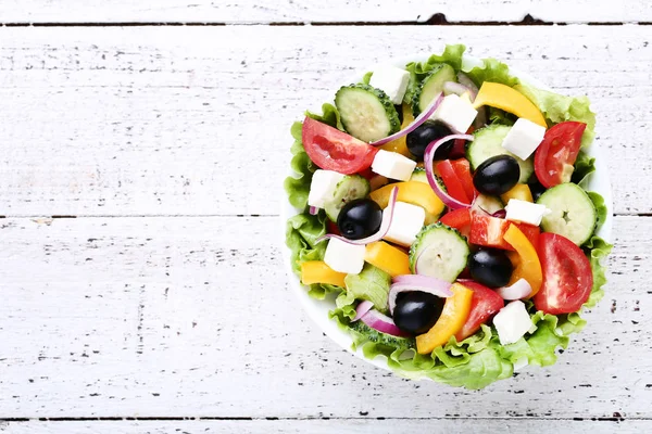 Beyaz ahşap masa üzerinde kase sebze salatası