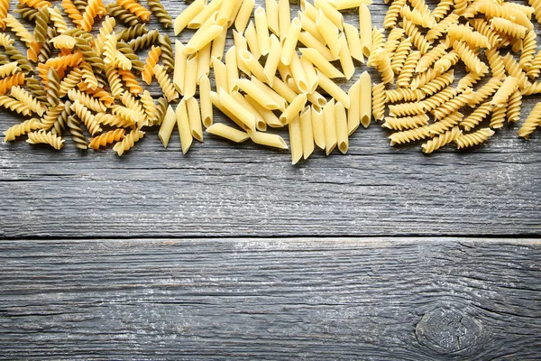 Gri ahşap masa üzerinde farklı pişmemiş makarna
