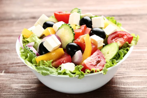 Kahverengi ahşap masa üzerinde kase sebze salatası