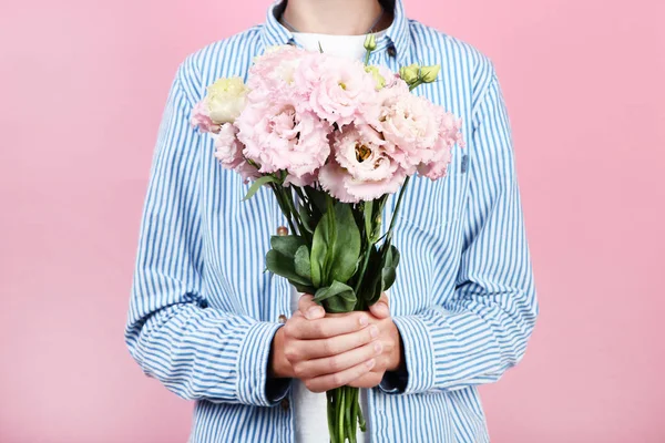 Pembe bir arka plan üzerinde eustoma çiçekli genç çocuk