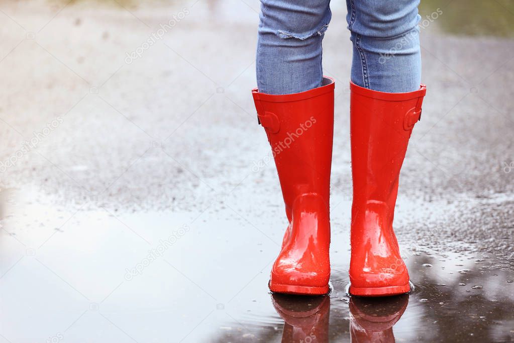 Woman wearing red rubber boots after rain