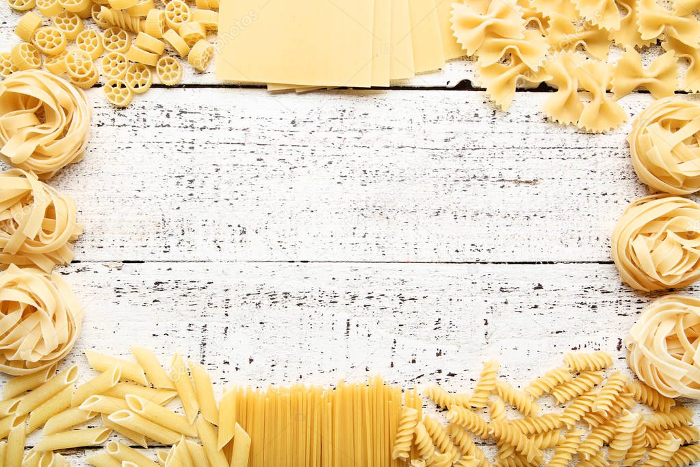 Different uncooked pasta on white wooden table