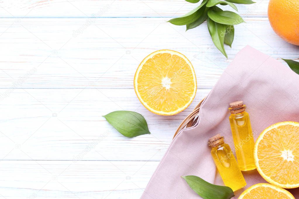 Orange oil in bottles with green leafs on wooden table