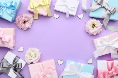 Şerit ve eustoma çiçekler mor arka plan üzerinde renkli hediye kutuları