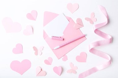 Kağıt kalp zarf ile pembe ve beyaz arka plan üzerinde kalem