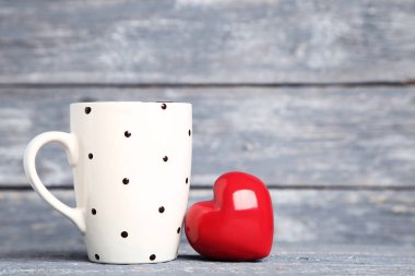 Gri ahşap masa üzerinde cup ile kırmızı kalp