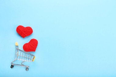 Mavi arka plan üzerinde kırmızı ip yürekleri alışveriş sepeti