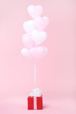 Pembe bir arka plan üzerinde hediye kutusu ile kalp balonlar