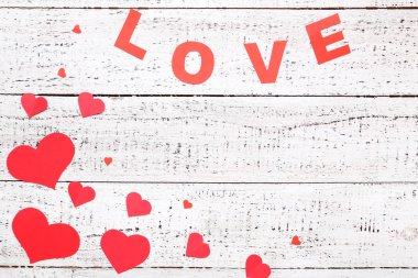 Beyaz ahşap masa üzerinde kelime aşk ile kırmızı kağıt kalpler