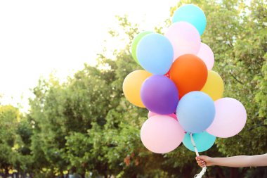 Renkli balonlar parkta tutan el
