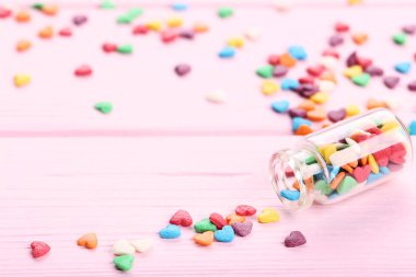 Pembe ahşap masa üzerinde cam şişe ile sprinkles renkli kalp şeklinde