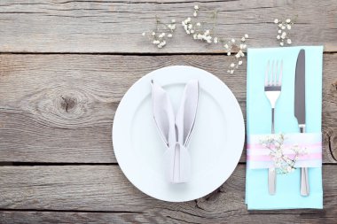 Gri ahşap masa üzerinde plaka ve gypsophila çiçekli mutfak bıçakları