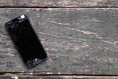 Gri ahşap masa üzerinde kırık smartphone