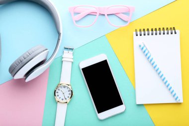 Kulaklıklar, gözlük ve renkli arka plan üzerinde defter ile Smartphone