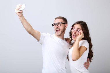 Güzel genç bir çift akıllı telefondan selfie çekiyor.