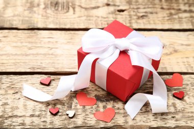 Şerit yay ve kalpleri kahverengi ahşap masa üzerinde hediye kutusu