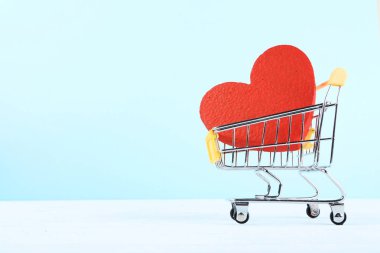 Alışveriş sepeti ile ahşap masa üzerinde kırmızı kalp
