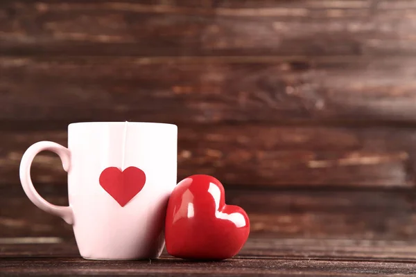 Red heart and cup with teabag on wooden table