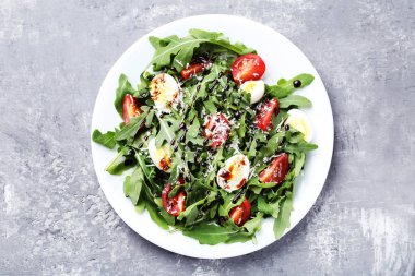 Roka salata yaprakları, domates ve gri ahşap masa üzerinde yumurta